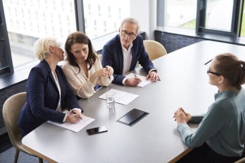 4 people sitting at a table taking notes