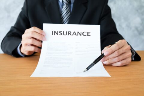 White man holding insurance paper with pen