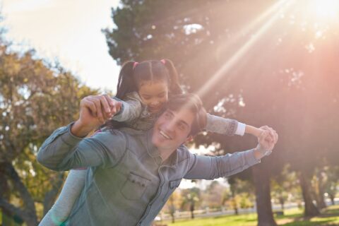 A father gives a ride on his back to his daughter